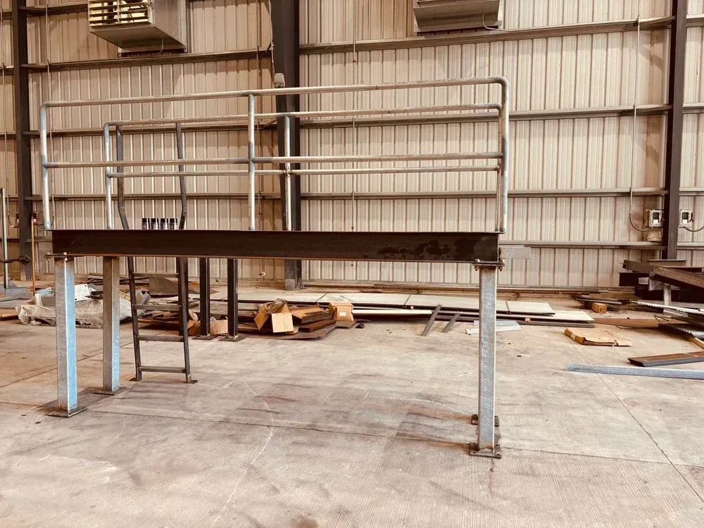 Metal platform with railing inside a warehouse; industrial setting.