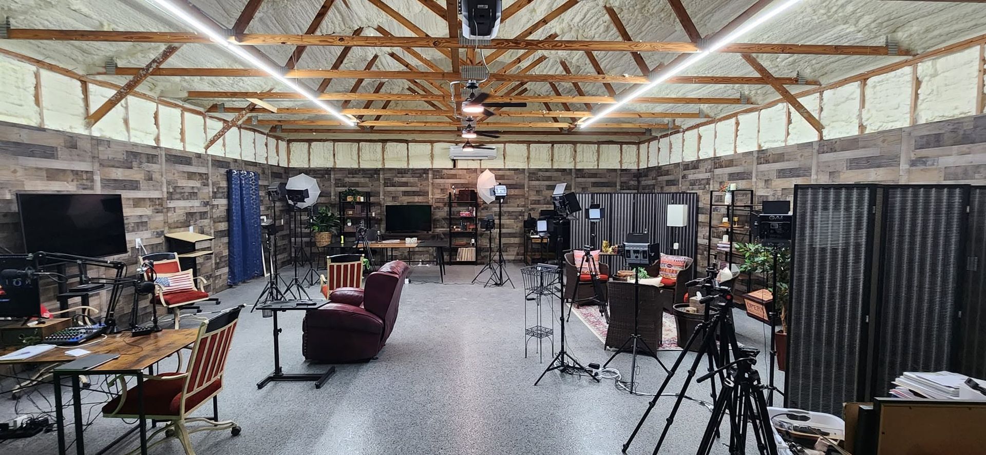 Wide studio workspace with cameras, tripods, desks, and computers under exposed wooden beams