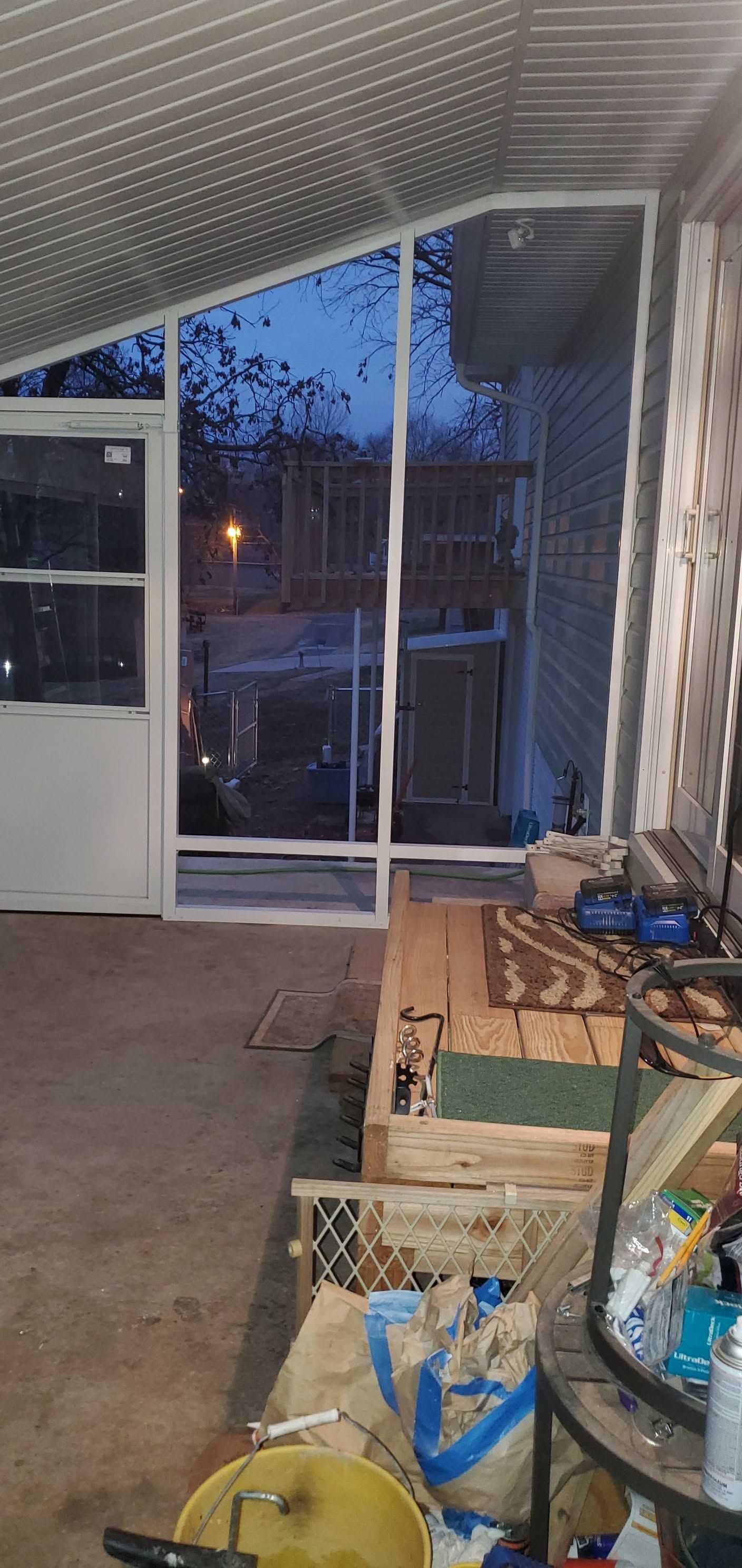 Messy indoor room with open doorway to a balcony or patio at dusk