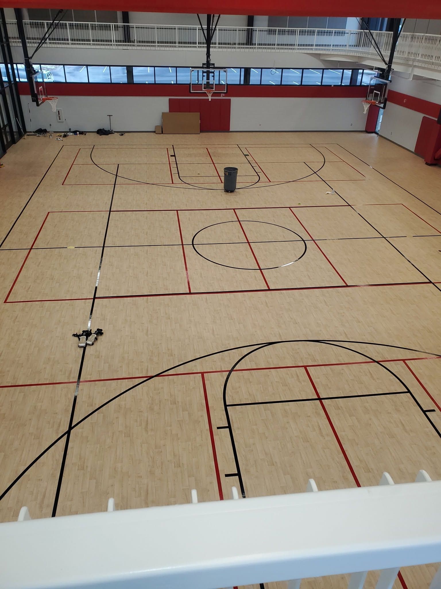 Indoor gymnasium with a marked court floor and a few small objects near the center.