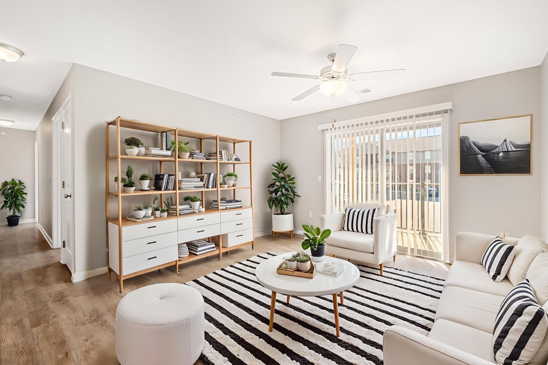 Bright modern living room with striped rug, white sofa, wooden shelf, and sliding glass doors to a balcony