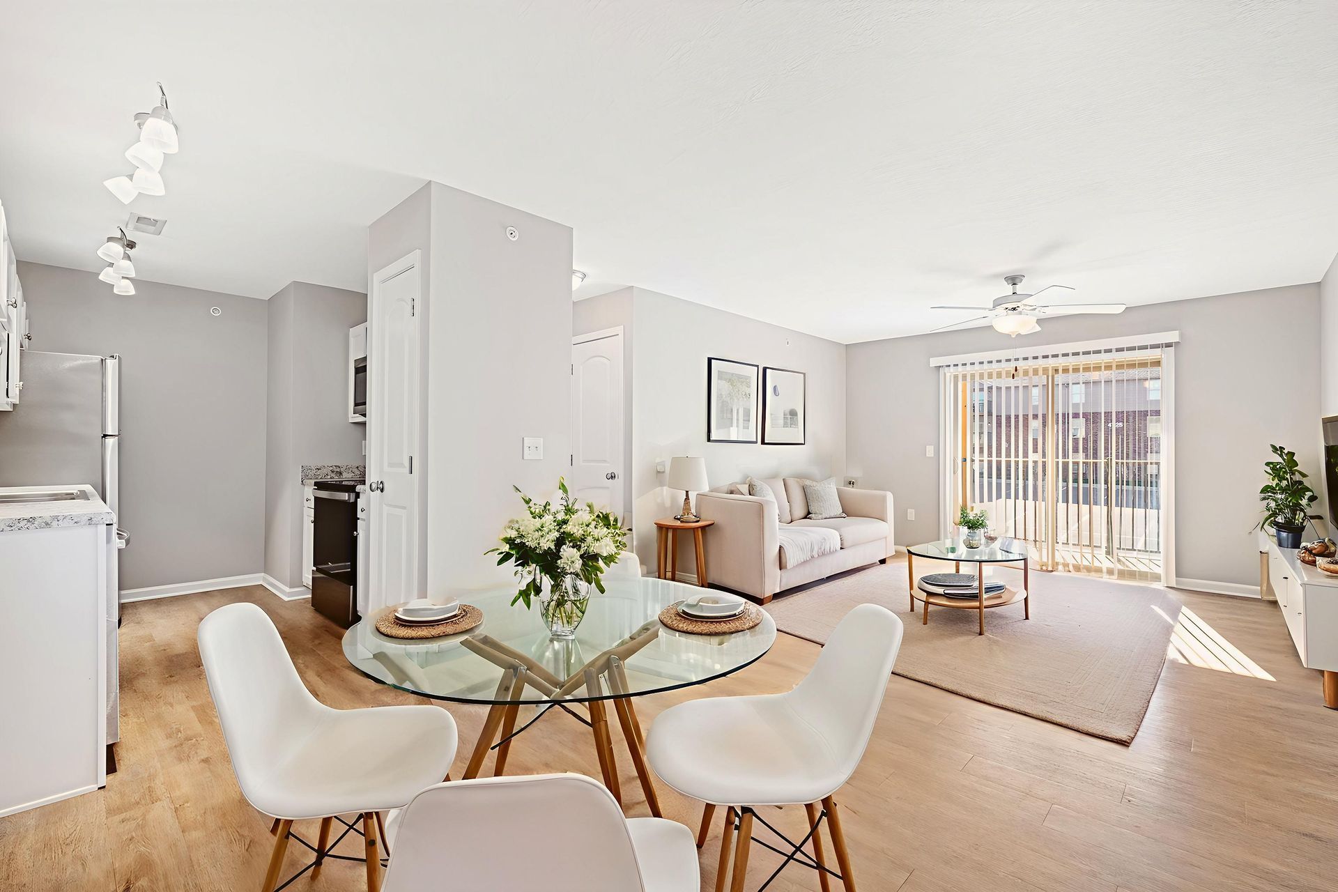 Bright open-plan living room with dining table, sofa, coffee table, and balcony doors.