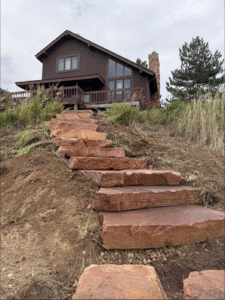 Stone steps up a dirt slope to a brown house on a cloudy hillside