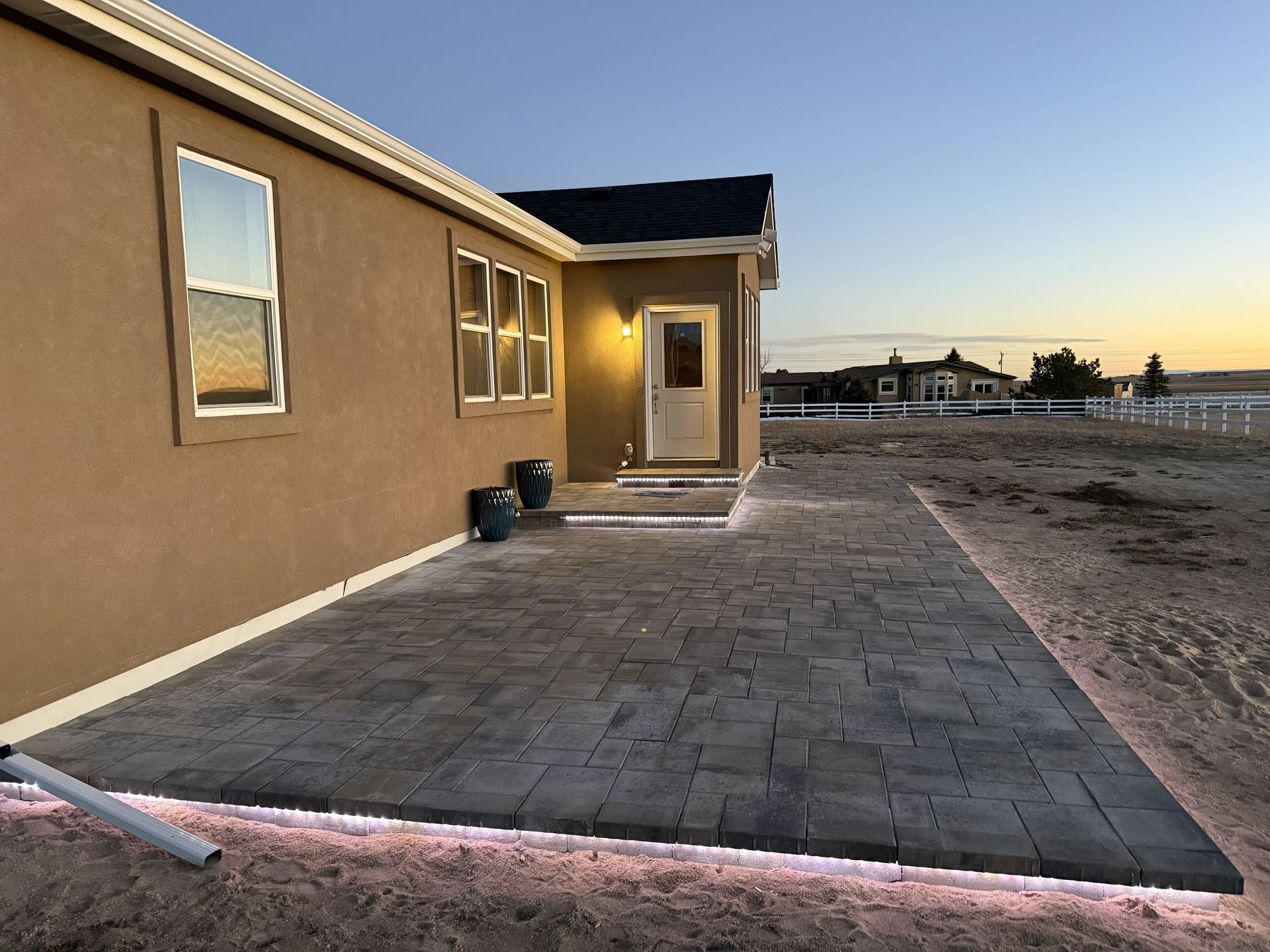 New house exterior with a paved patio and sunset sky