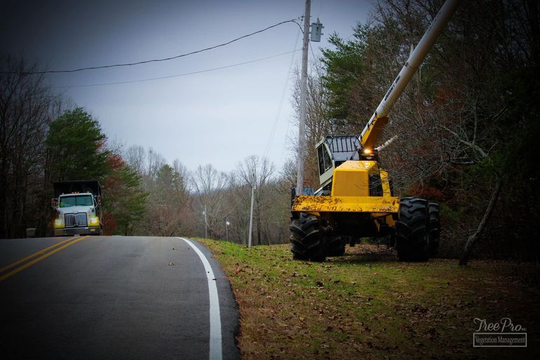Yellow utility truck on a rural roadside beside a paved road and power lines Yellow utility truck on a rural roadside beside a paved road and power lines