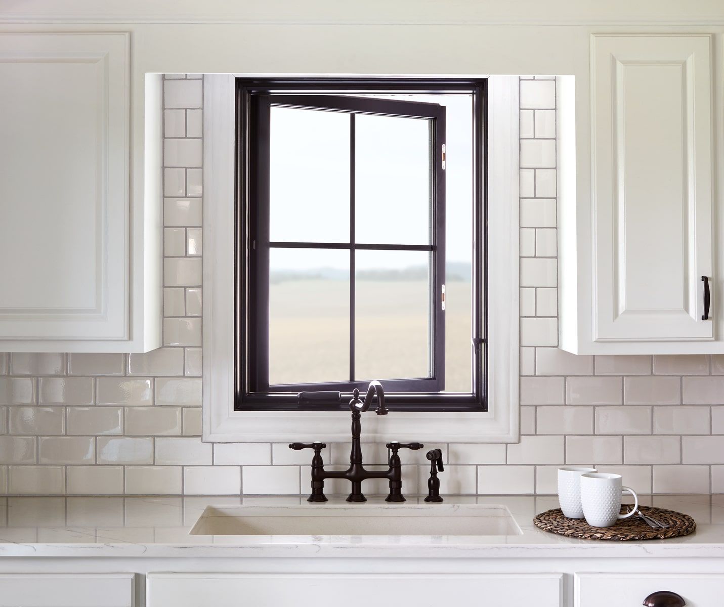 A kitchen with white cabinets a sink and a window