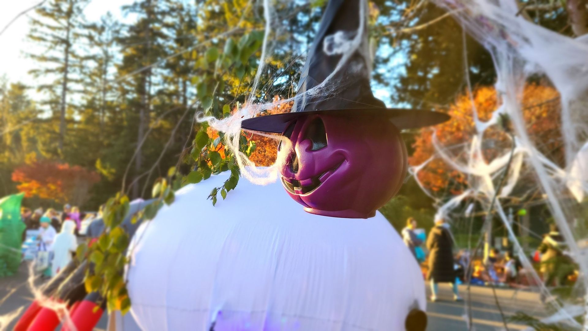 A large inflatable witch is hanging from a tree.