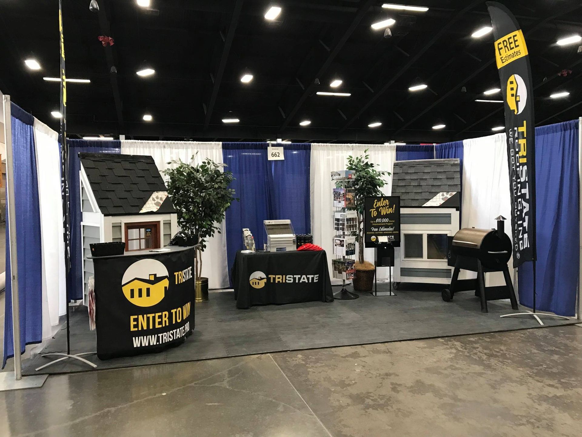A booth at a convention with a small house and a table.