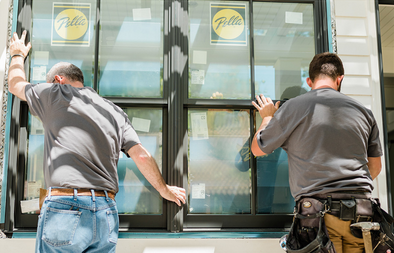 Two men are installing a window on a building.