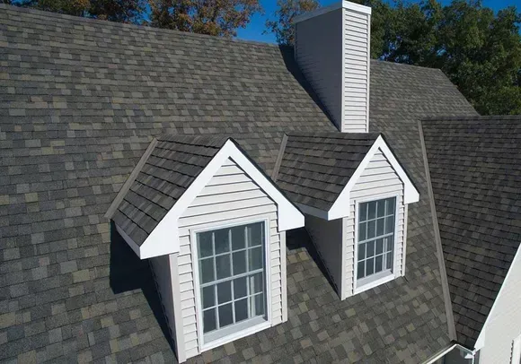 The roof of a house with two windows and a chimney.