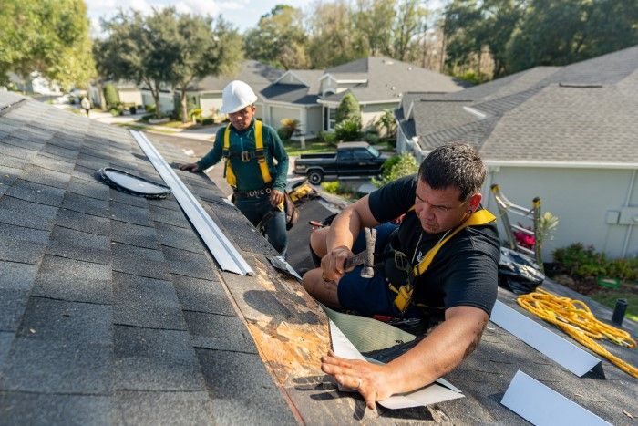 Two men are working on a roof of a house.