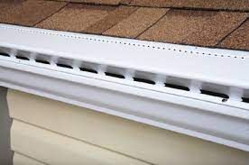 A white gutter on the side of a house with a brown roof.