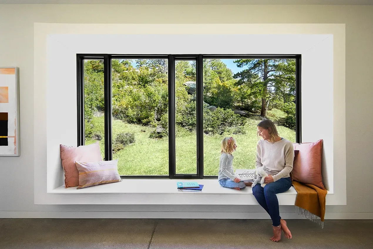 A woman and a child are sitting on a window sill.