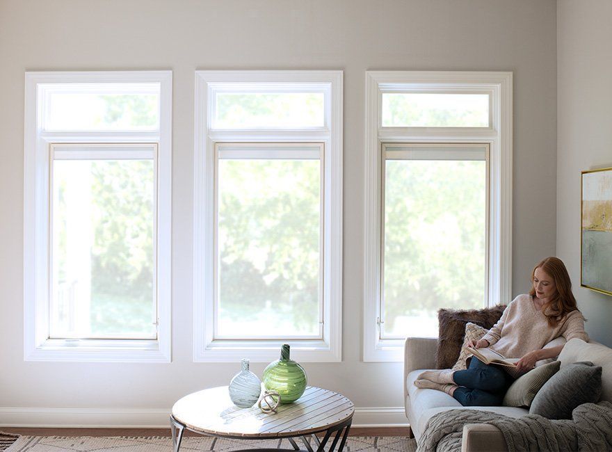 A woman is sitting on a couch in a living room reading a book.