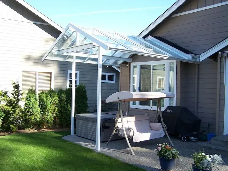 A backyard with a swing and a hot tub under a canopy
