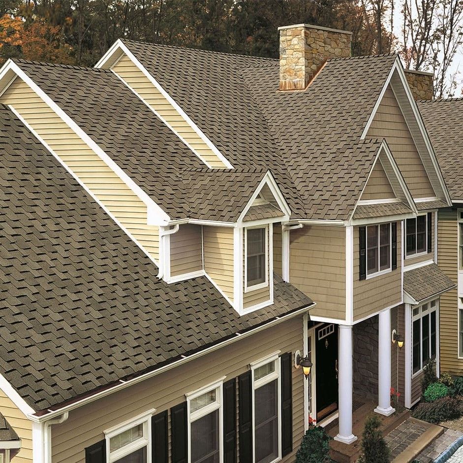 A large house with a tan siding and a brown roof