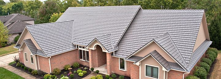 An aerial view of a large brick house with a gray roof.