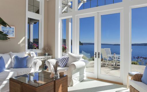 A living room with a lot of windows and a view of the ocean.