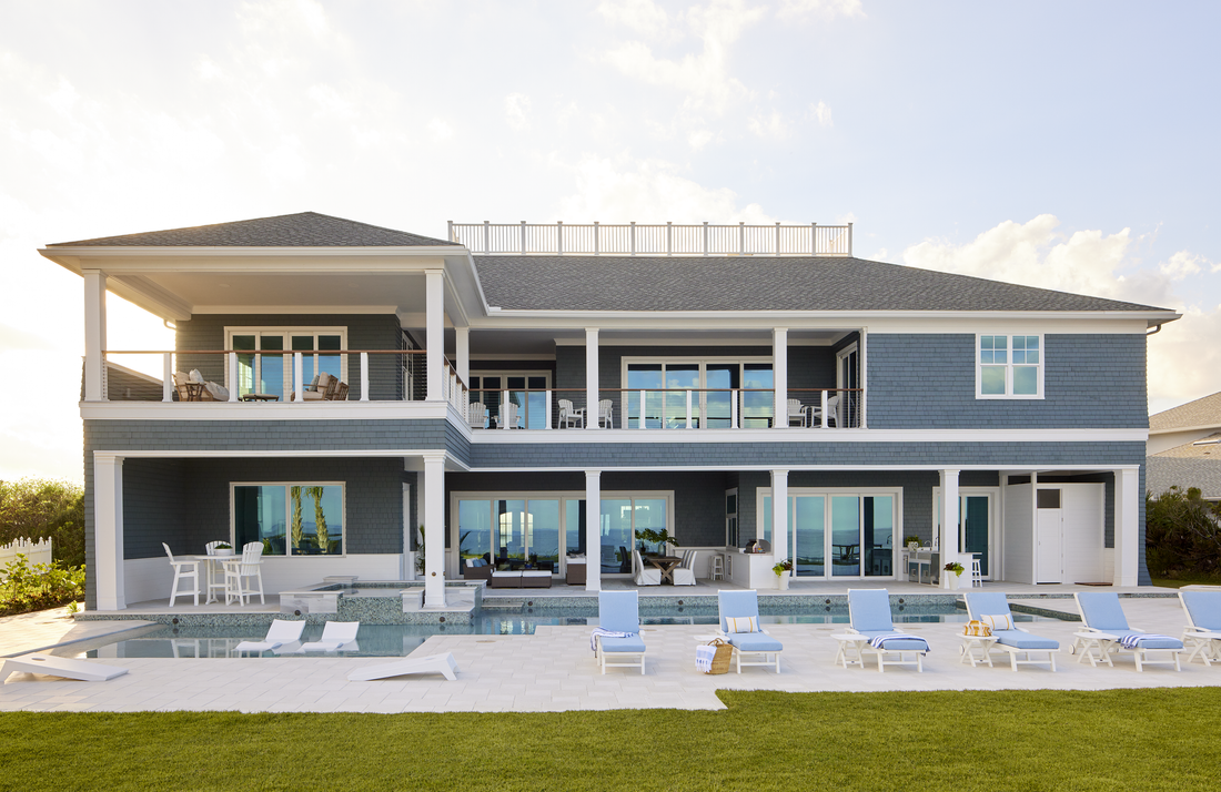 A large house with a swimming pool and chairs in front of it