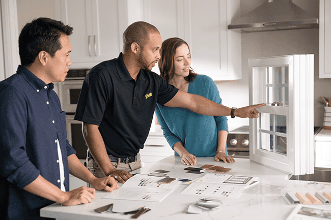 A group of people are looking at a window in a kitchen.