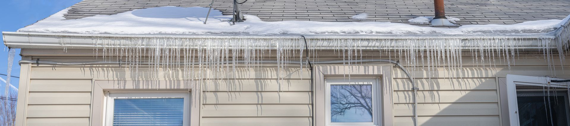 Icicles are hanging from the roof of a house.