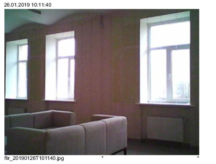 Three white-framed windows in a room with a beige sofa and a radiator, likely indoors.