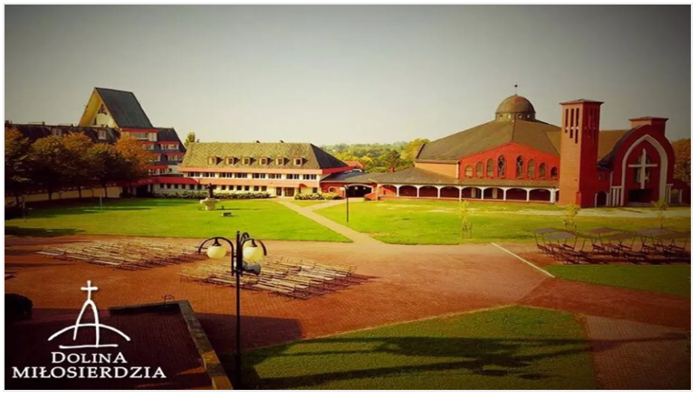 Complex of buildings with grass and a logo in the foreground.