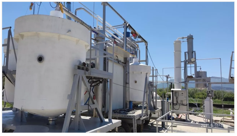 White industrial tanks and piping outdoors under a blue sky.