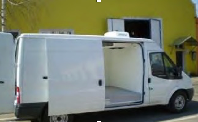 White refrigerated delivery van with open side door parked outside a yellow building.