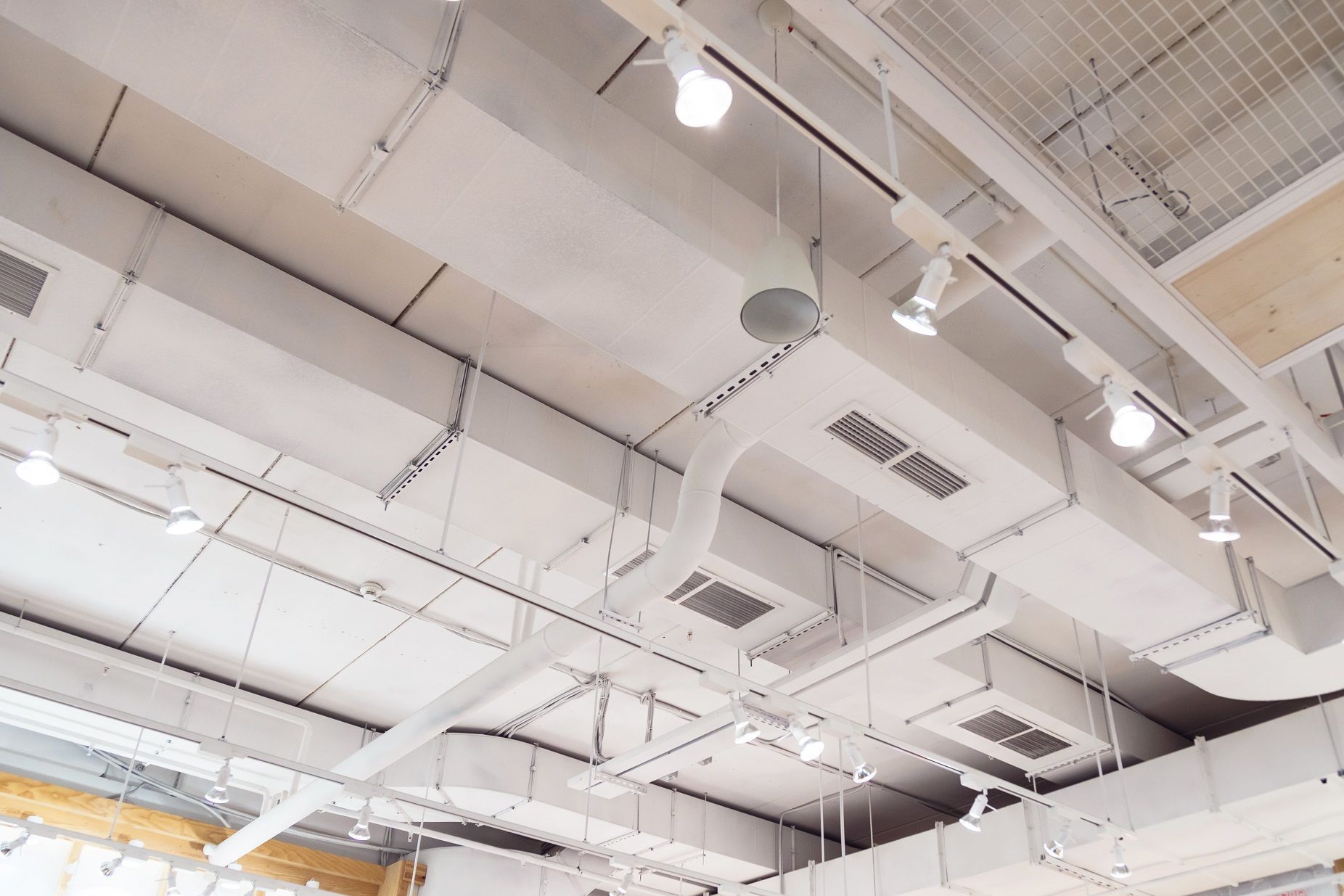 White ceiling with exposed air ducts, lighting, and vents.