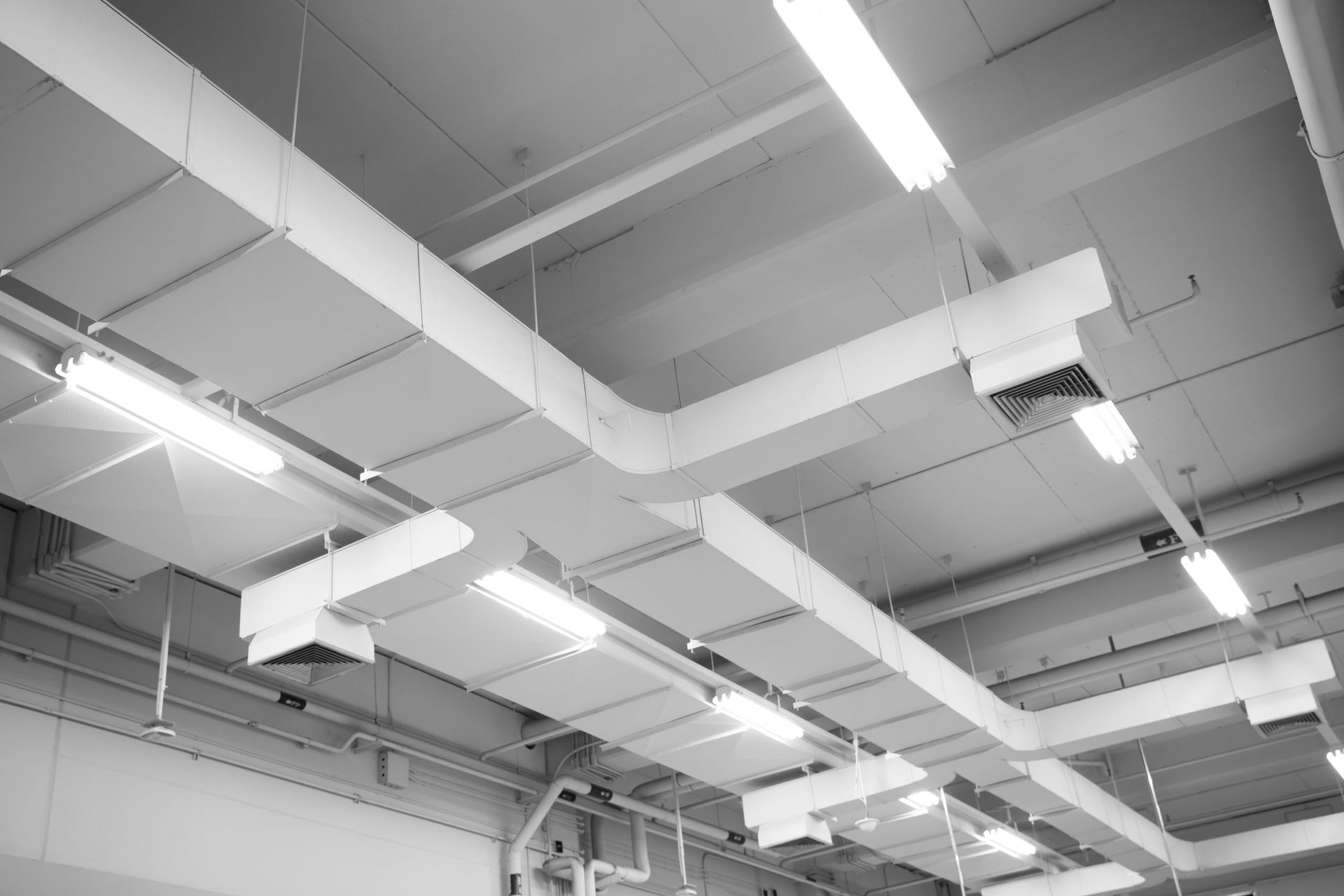 White ceiling with rectangular HVAC ducts and fluorescent lights.