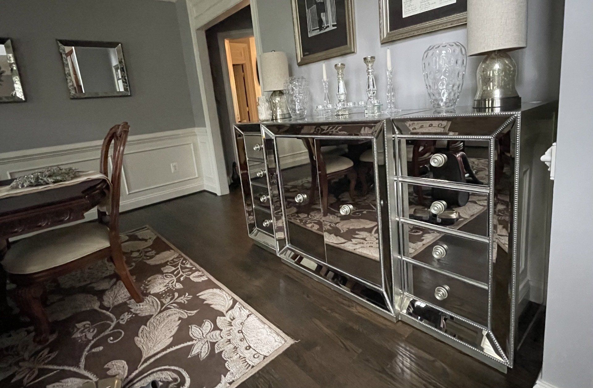 Elegant dining room with mirrored console table, dark wood floor, and patterned rug