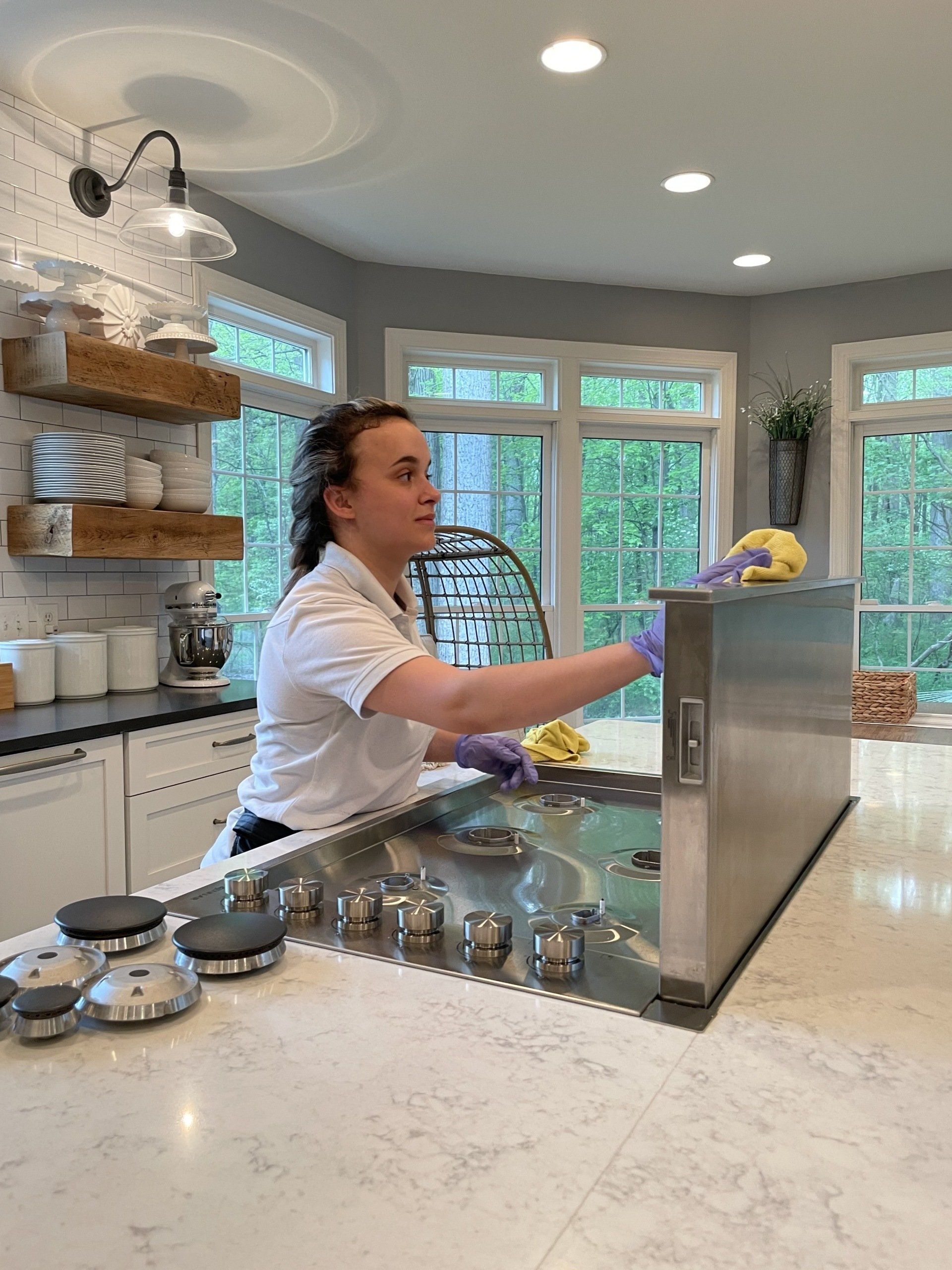 Person serving drinks in a bright, modern kitchen with a marble island and large windows