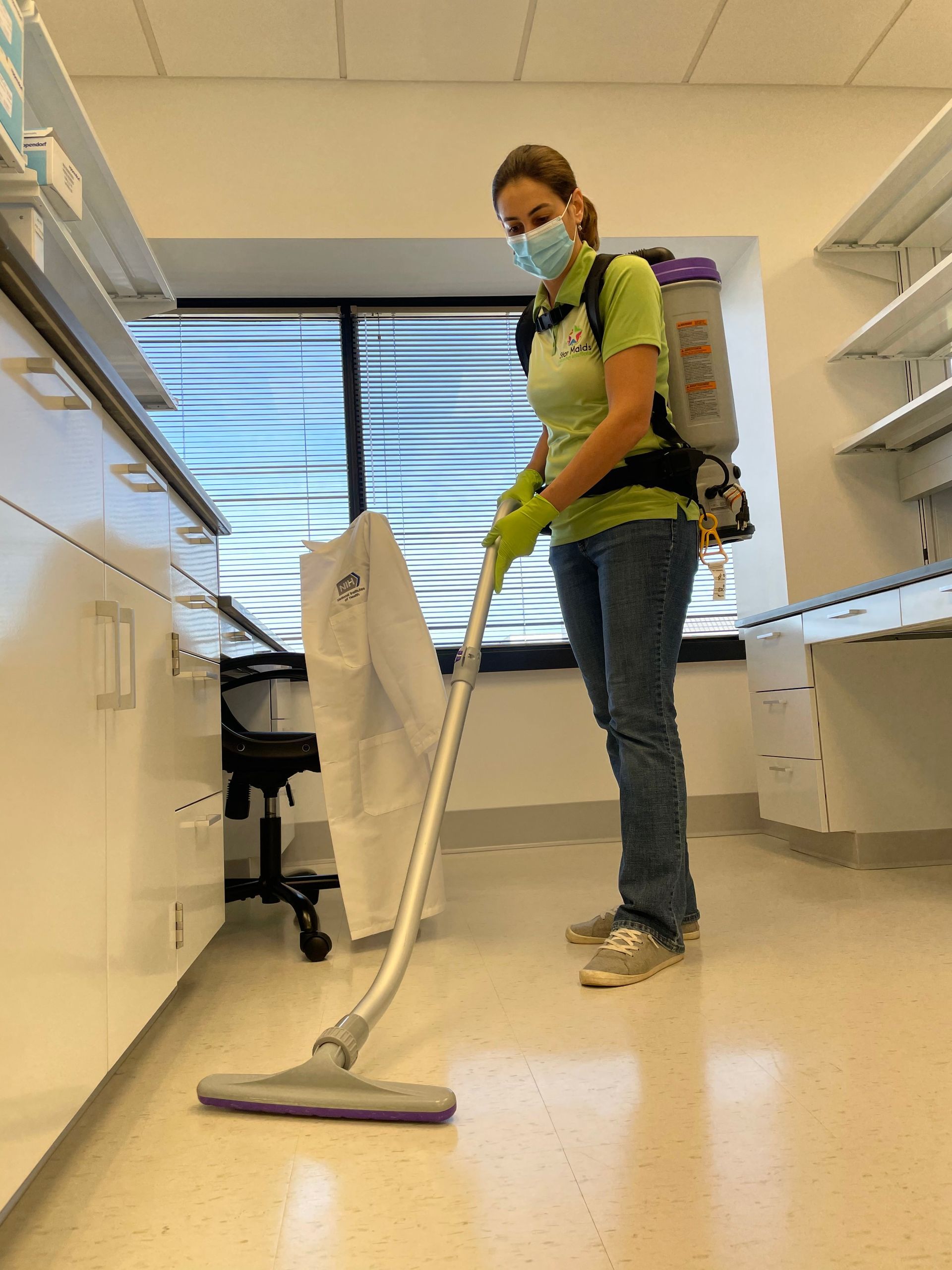 Person mopping a lab floor while wearing gloves and a face mask