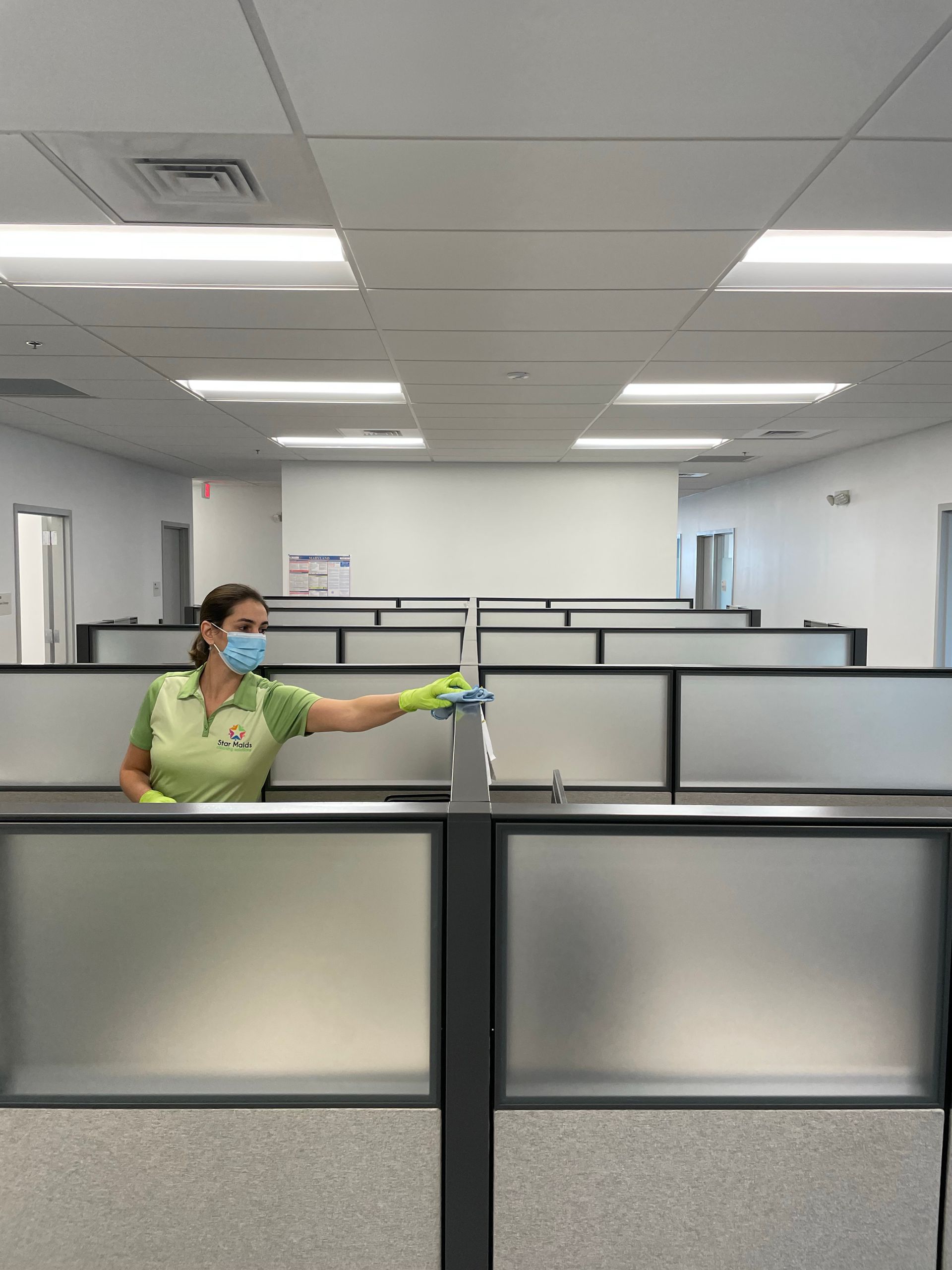 Floor Vacuum - Olney, Maryland - Star Maids Cleaning Solutions LLC Person in a mask and gloves cleaning office cubicles with a spray bottle