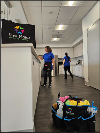 Maids cleaning an office hallway with a Star Maids bucket and supplies in the foreground