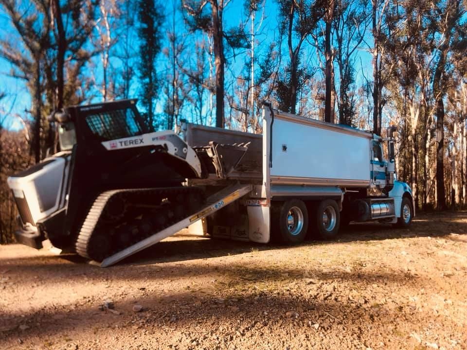 A bulldozer is being towed by a dump truck.