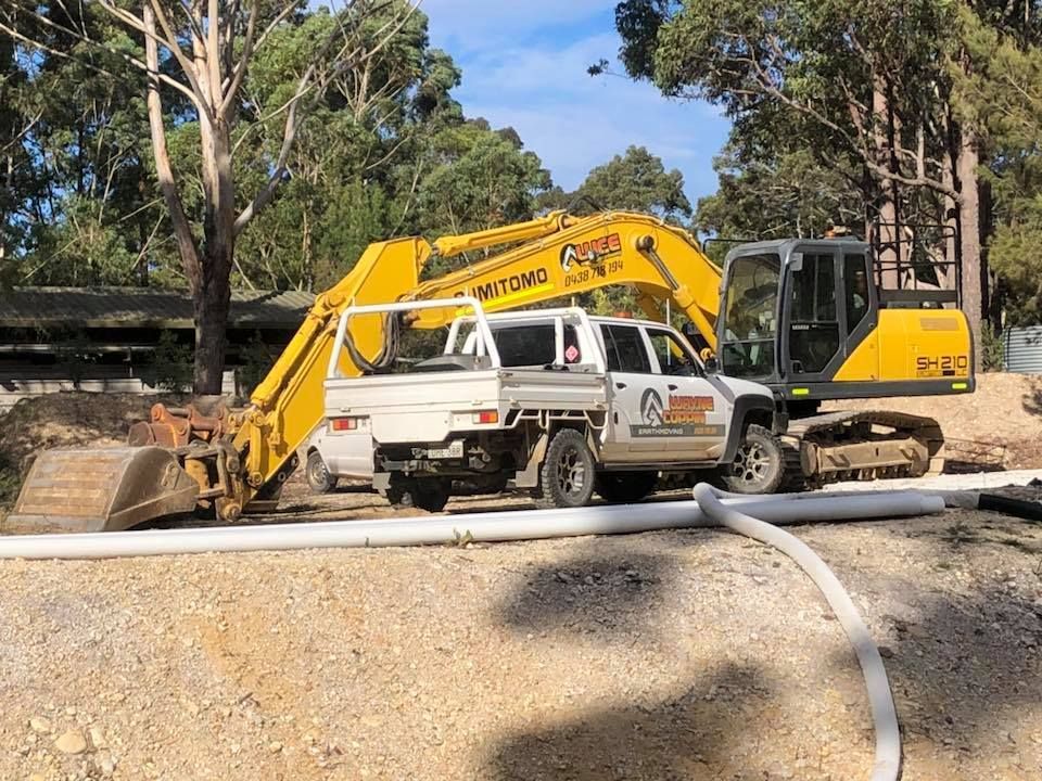 A yellow excavator is parked next to a white truck.