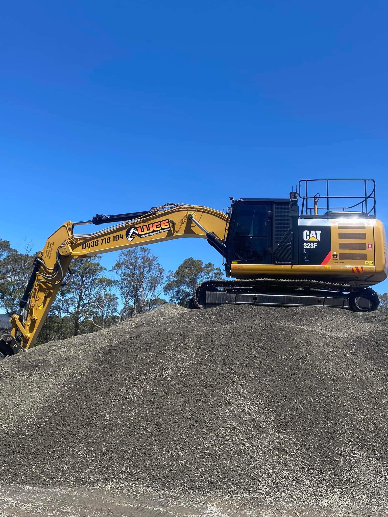 A large excavator is sitting on top of a pile of gravel.
