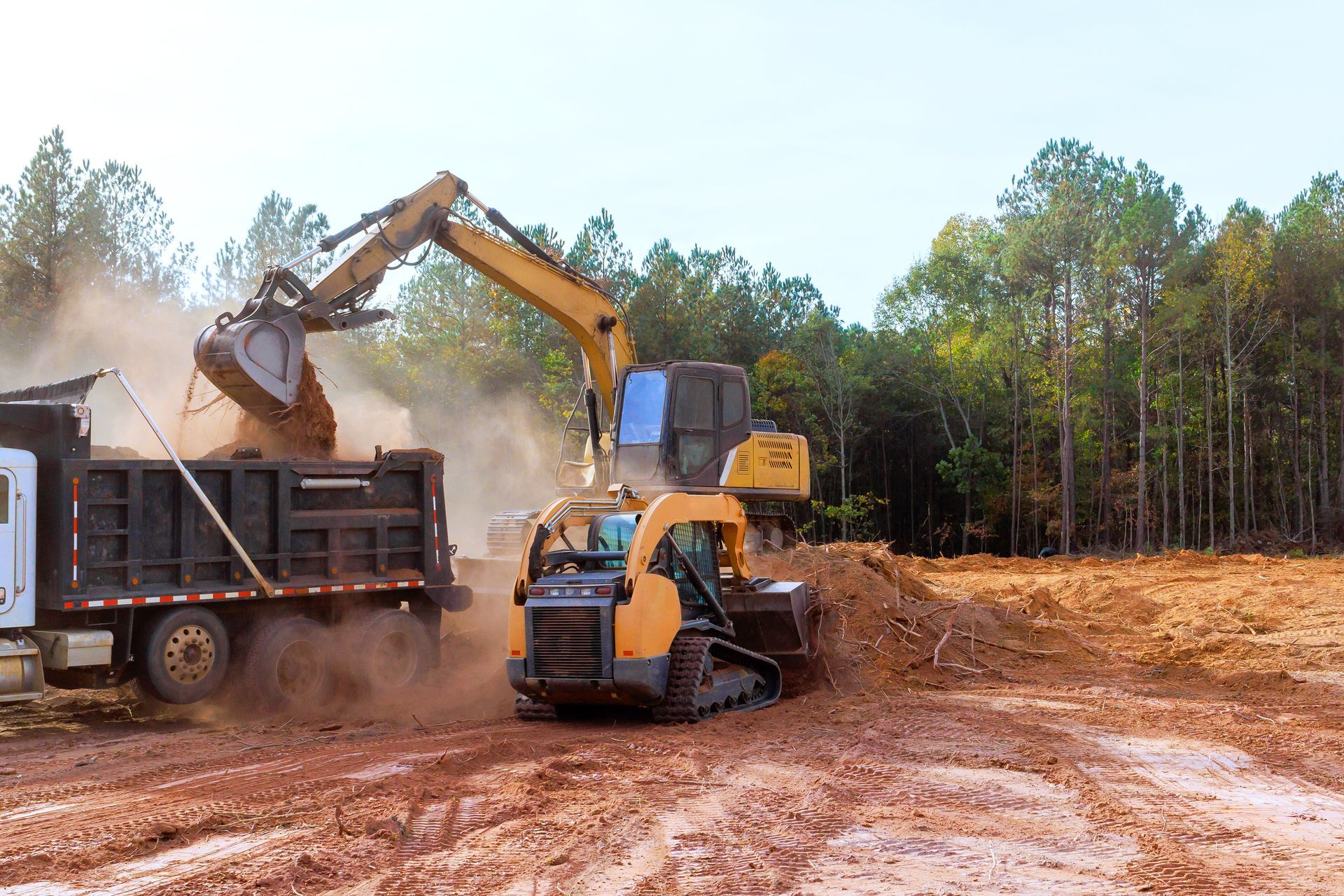 A bulldozer is loading dirt into a dump truck.