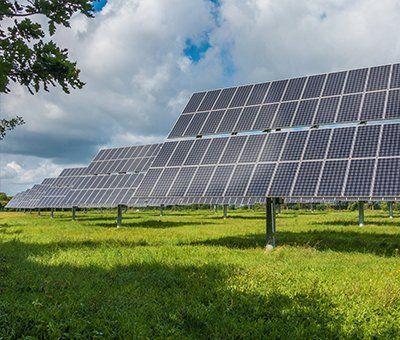 A row of solar panels are sitting in a grassy field.