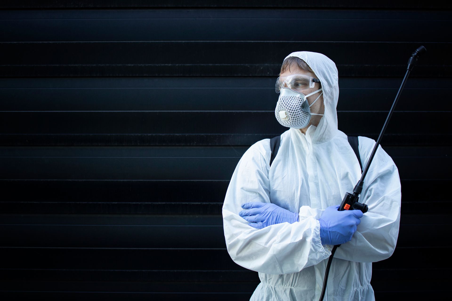 Commercial pest control technician in protective suit holding a sprayer