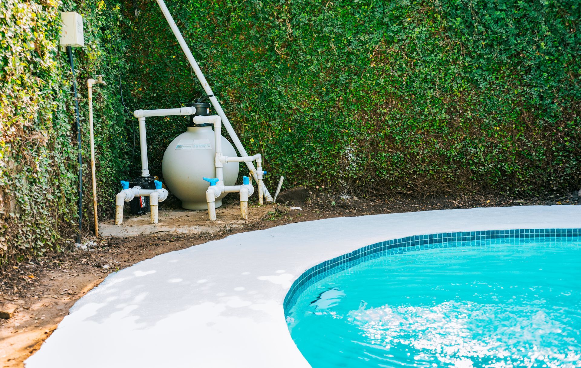 Residential pool pump and filtration system beside backyard swimming pool for maintenance solutions.