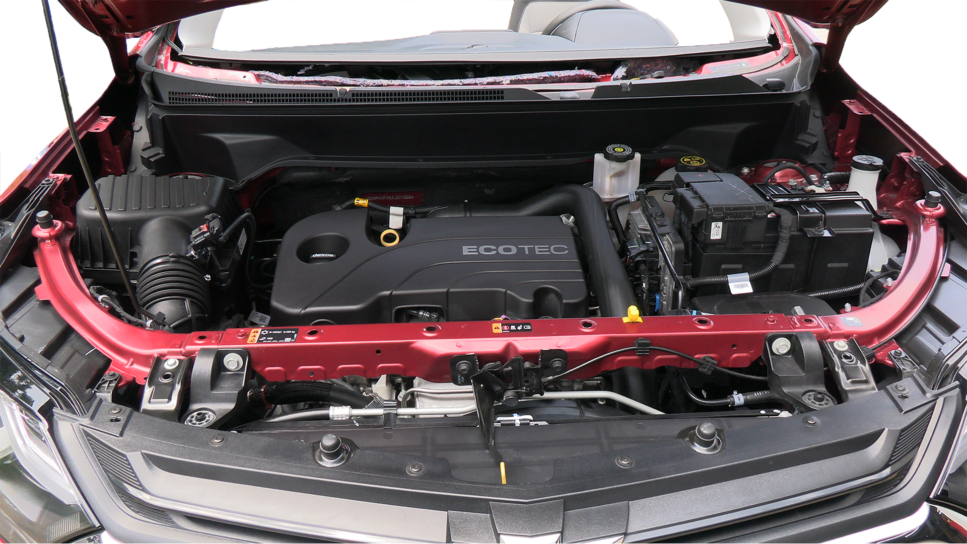 The engine of a red car is shown with the hood open.