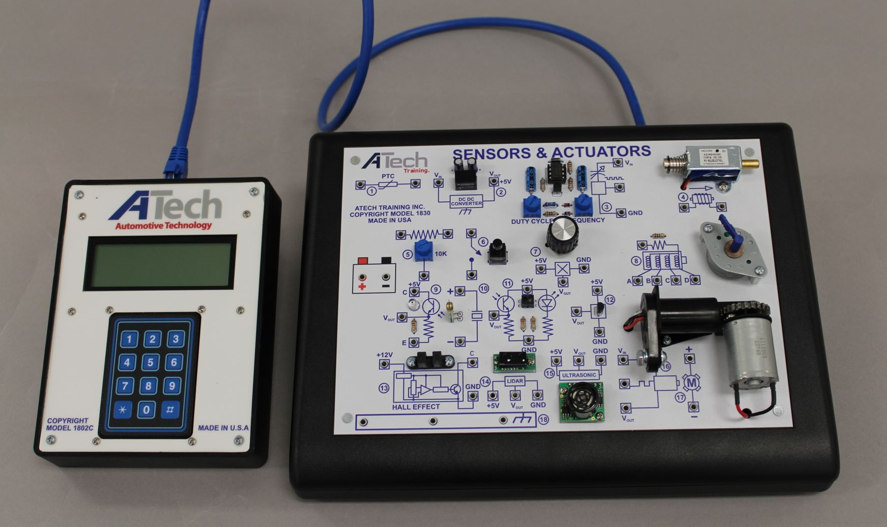 Electronics training equipment: control panel and circuit board connected by a blue cable.