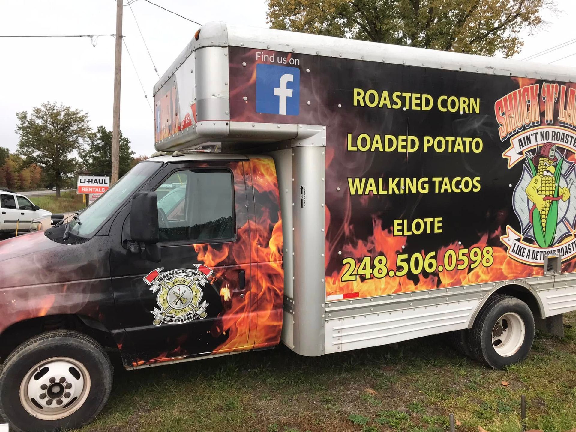 Food truck with flame graphics advertising roasted corn, loaded potato, and walking tacos parked outdoors