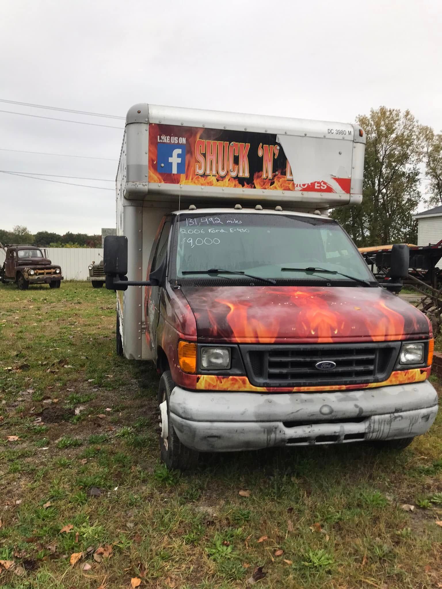 Old orange-and-black box truck parked on grass at an outdoor lot