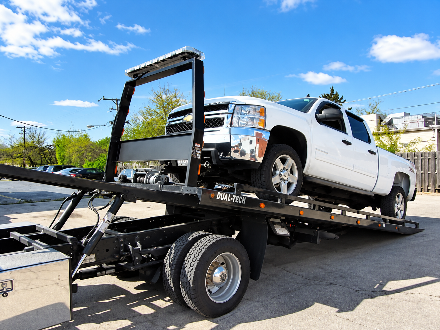 Tow truck hauling a broken-down black SUV on a roadside with two workers nearby