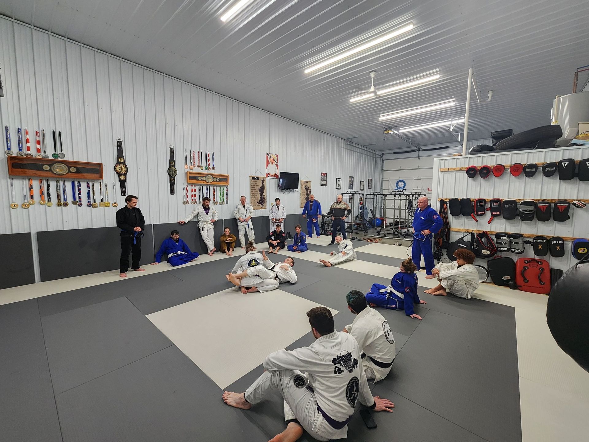 A group of people are sitting on a mat in a gym.