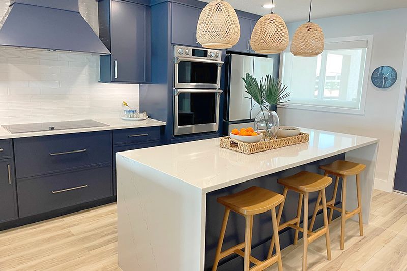 A kitchen with blue cabinets , white counter tops , stools and a large island.